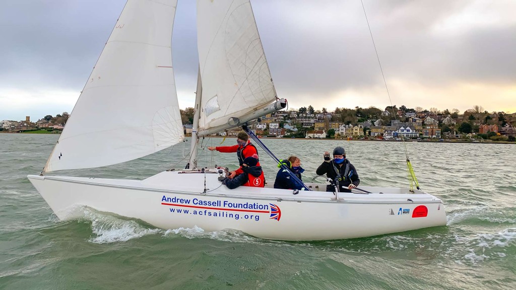 A sonar runs downwind out of the river Medina at Cowes with four people on board