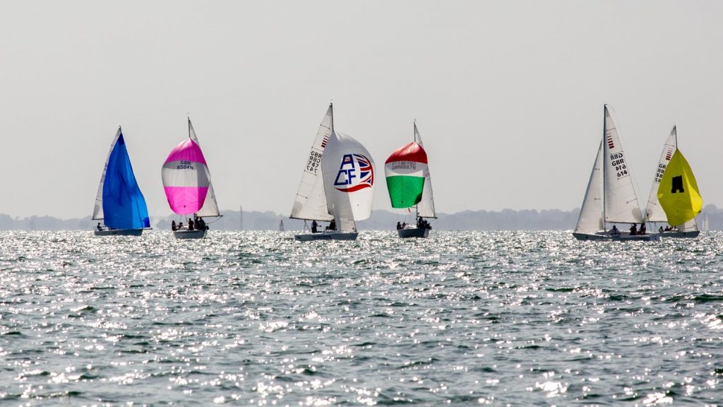 An ACF Sonar running under spinnaker sails downing in company with a collection of other boats from different classes 